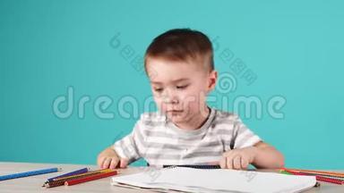 年轻有才华的男孩在蓝色背景的相册里画了一幅铅笔画。